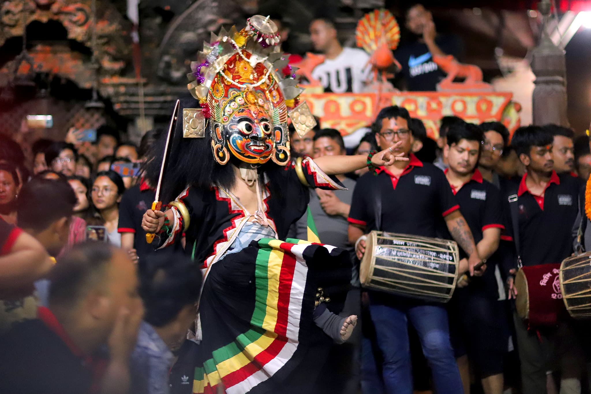 Masked Bhaila performance in a festive Thimi street setting.